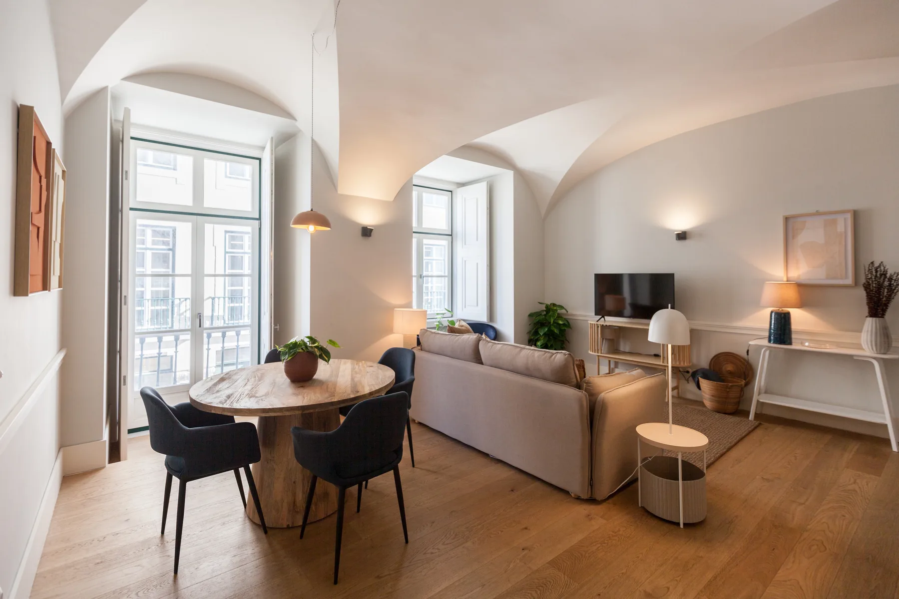 Sala de estar y comedor con asientos alrededor de una mesa y un televisor.