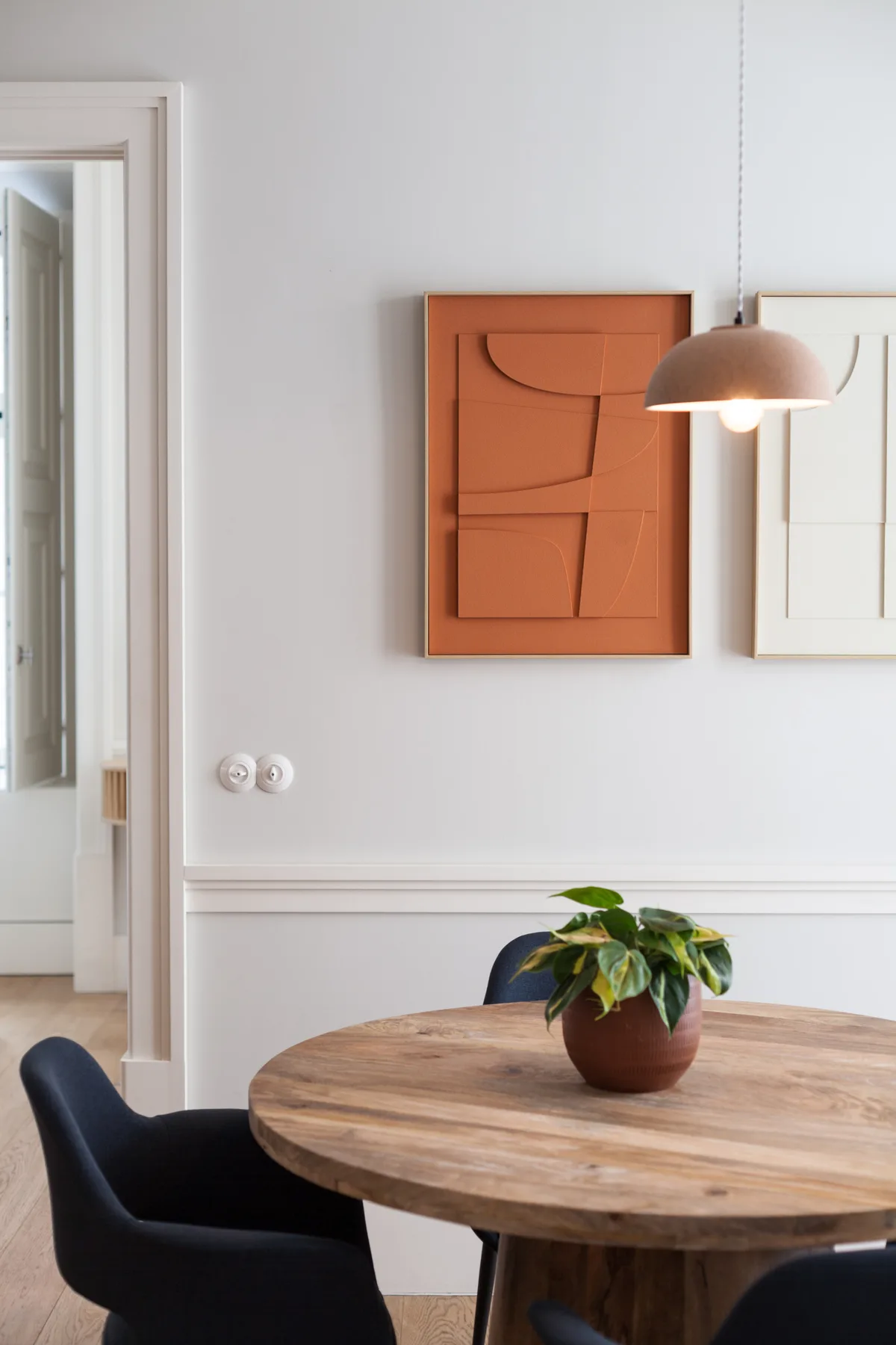 Comedor con una mesa redonda de madera, asientos y una planta en maceta.
