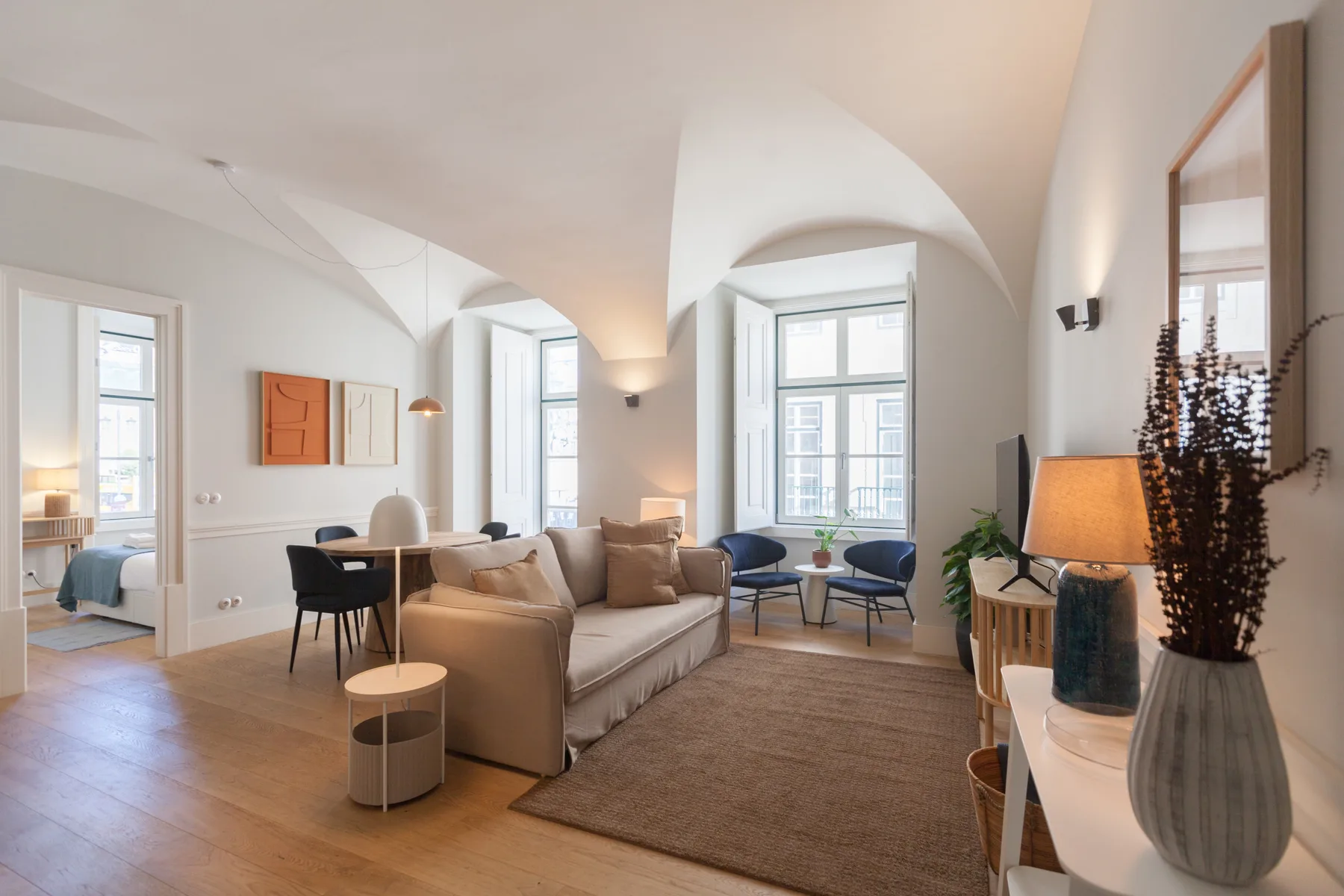 Una sala de estar luminosa con asientos y ventanas grandes.