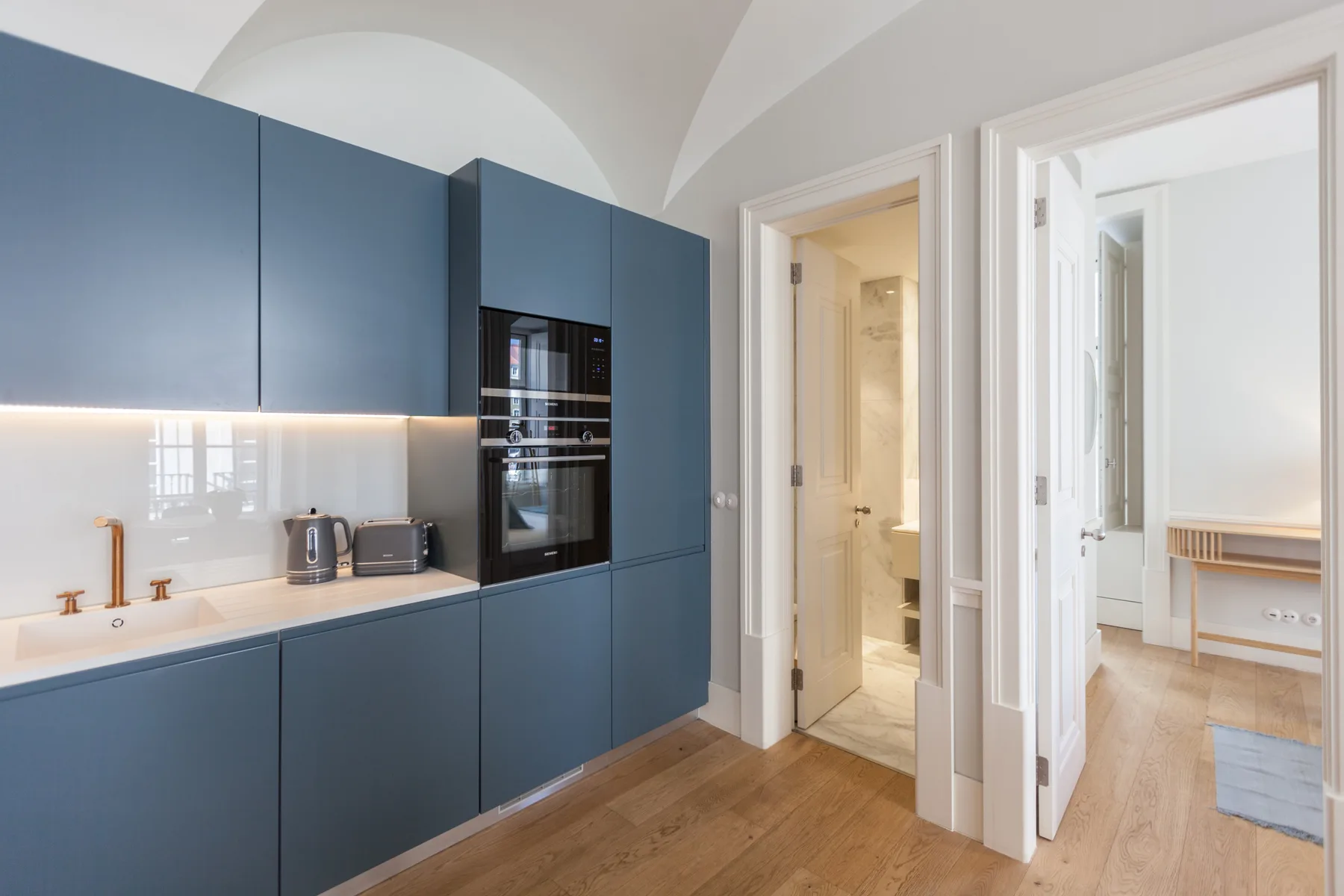 Una cocina moderna con gabinetes azules se abre a una habitación luminosa.