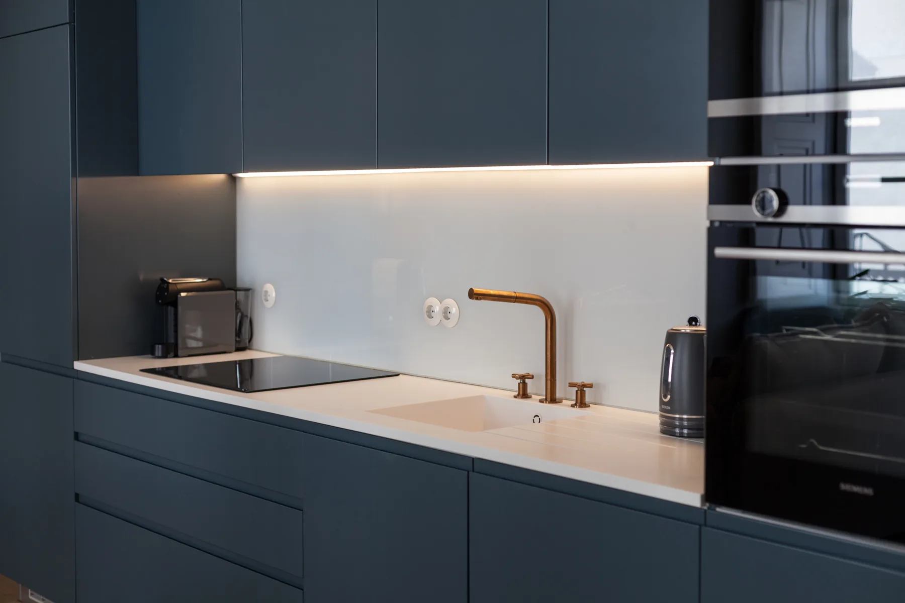 Una cocina moderna con gabinetes oscuros, fregadero y electrodomésticos sobre la encimera.