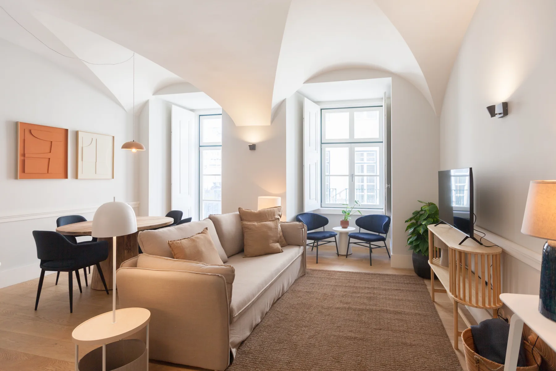 Una sala luminosa con asientos, un comedor y ventanas grandes.