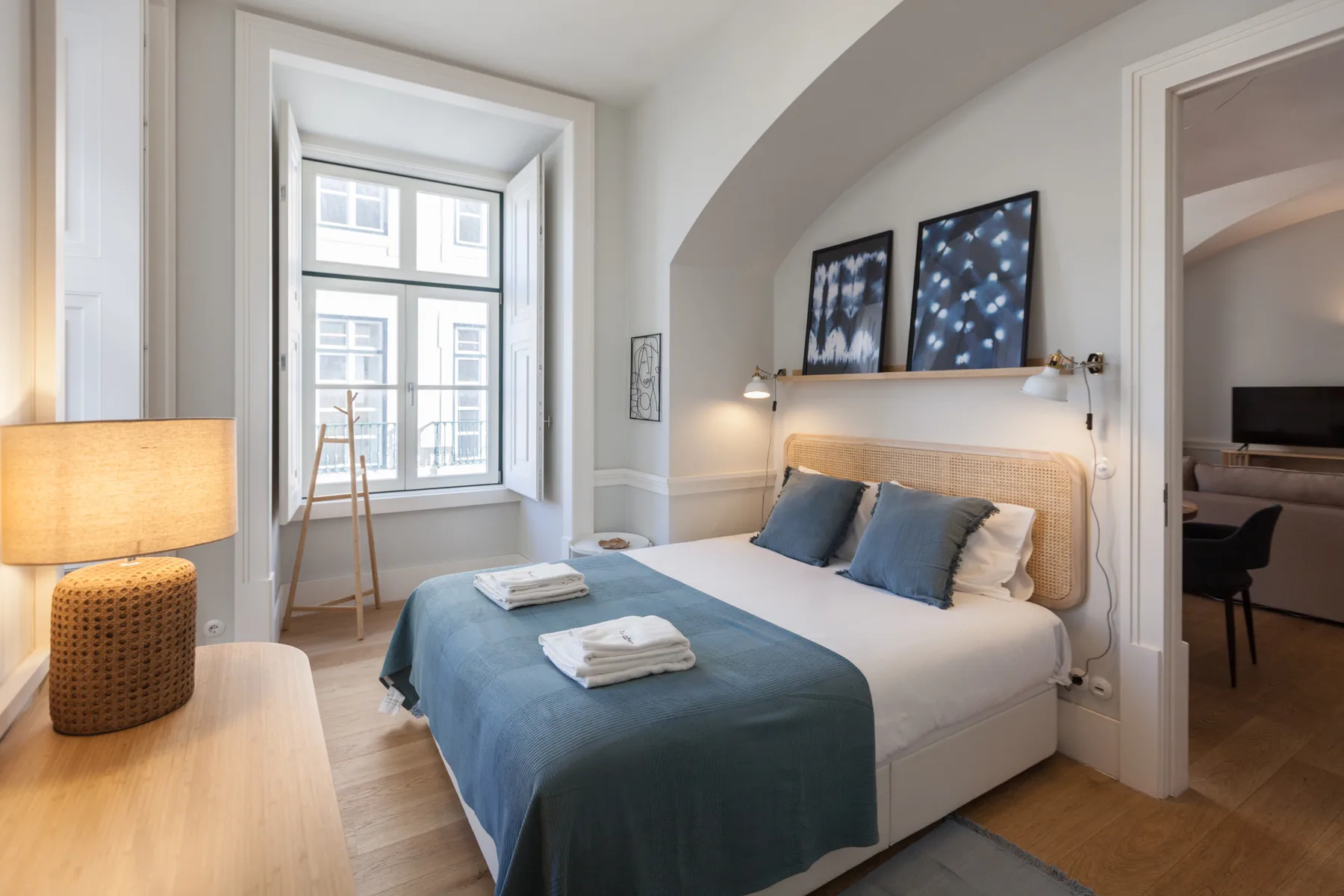 Un dormitorio con una cama vestida de azul y una ventana grande.