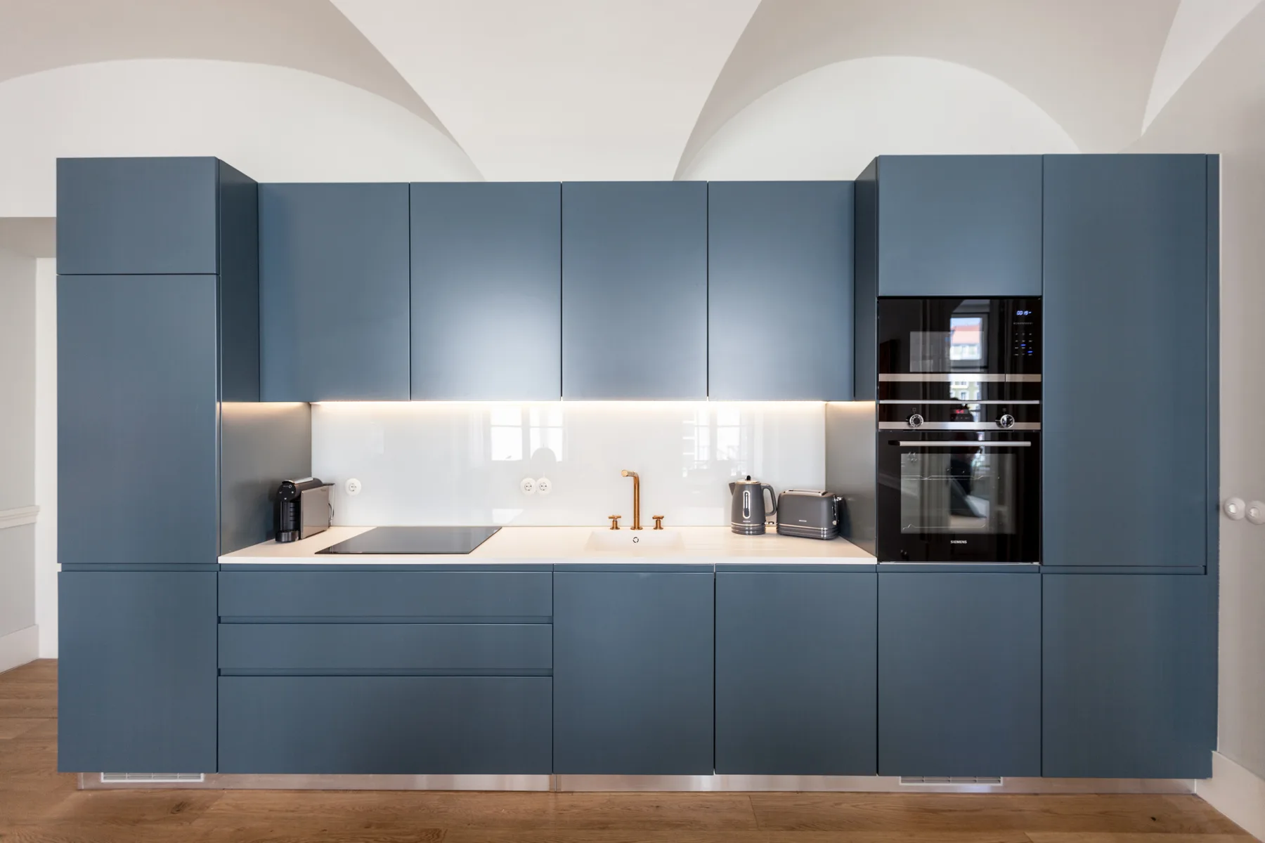 Una cocina moderna con armarios azules, una encimera y electrodomésticos integrados.