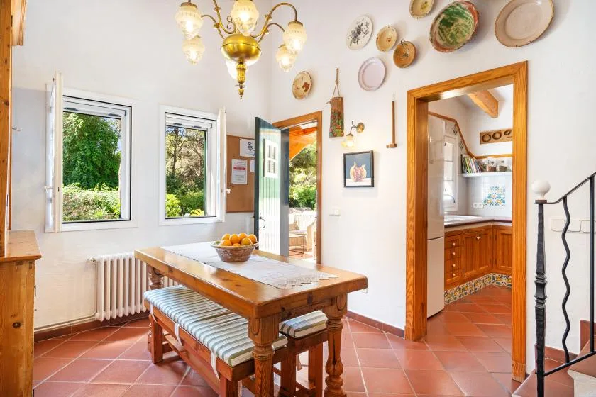 A bright dining room with a wooden table, windows, and an open doorway.
