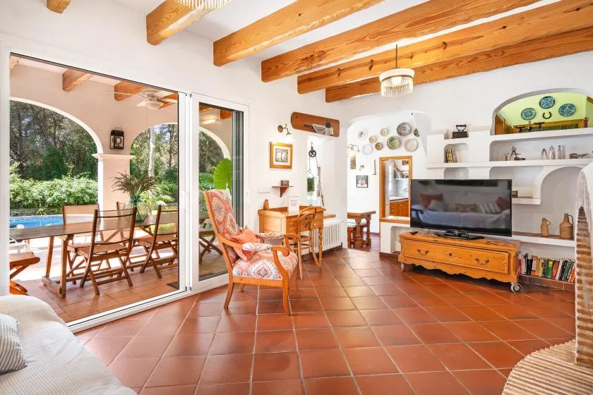 A living room with exposed wooden ceiling beams and a television.