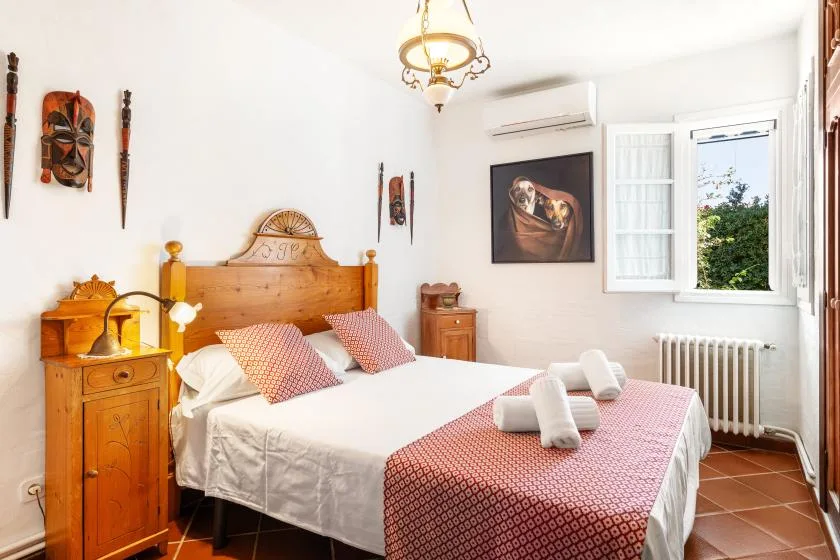 A bedroom with a wooden bed, patterned bedding, and an open window.
