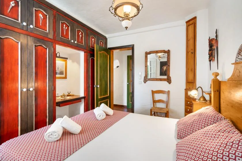 A bedroom with a large bed and dark wood wardrobes.