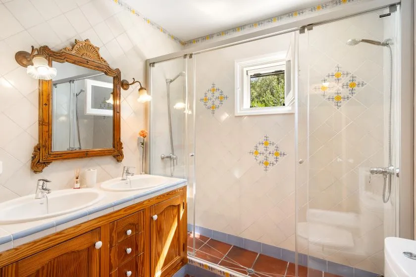 A bathroom with a wooden vanity and a glass shower.