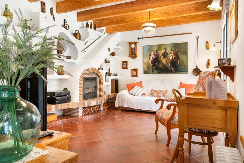 A living room with tiled flooring, wooden ceiling beams, and seating.
