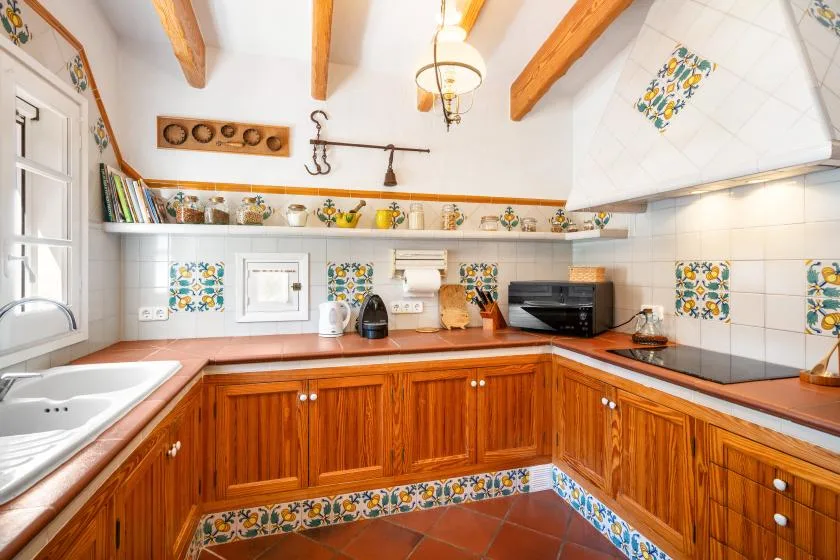 A tiled kitchen with wooden cabinets, a countertop, and a sink.