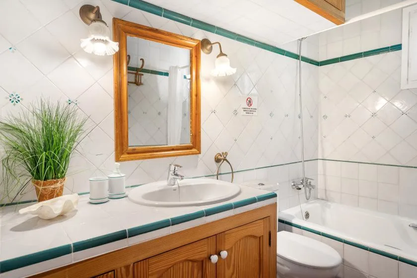 A tiled bathroom with a sink, wooden vanity, and bathtub.