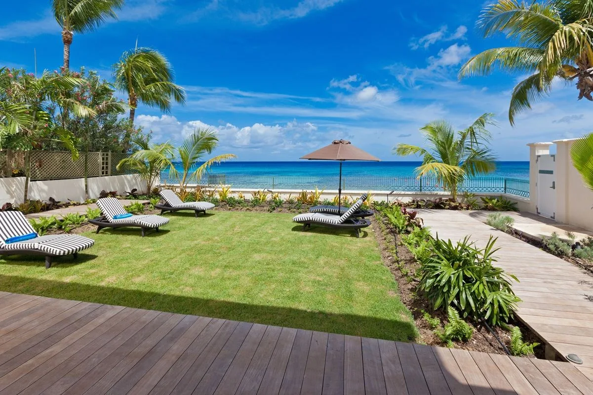 A landscaped seaside lawn with lounge seating and a view of the ocean.