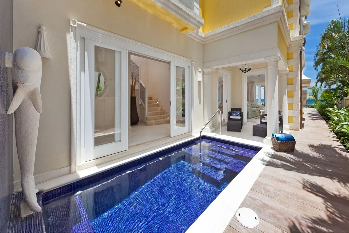 Una pequeña piscina de azulejos azules está junto a un patio cubierto y luminoso.