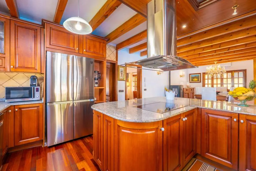 Una cocina con gabinetes de madera, una isla central y electrodomésticos de acero inoxidable.