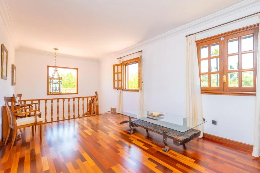 Una sala luminosa con suelo de madera pulida y ventanas grandes.