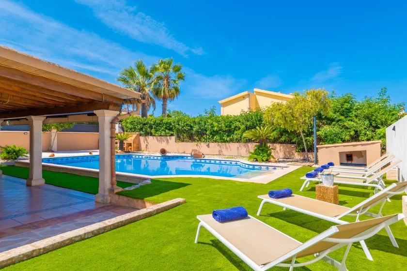 Una piscina en el patio con tumbonas y un patio sombreado.