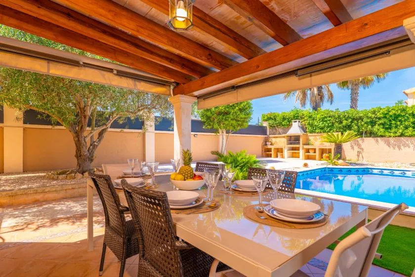 Una zona de comedor exterior cubierta con una mesa junto a una piscina.