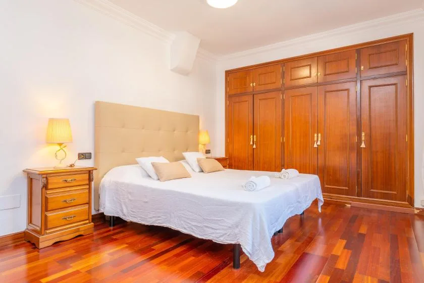 Un dormitorio con una cama, una mesita de noche y armarios empotrados de madera.