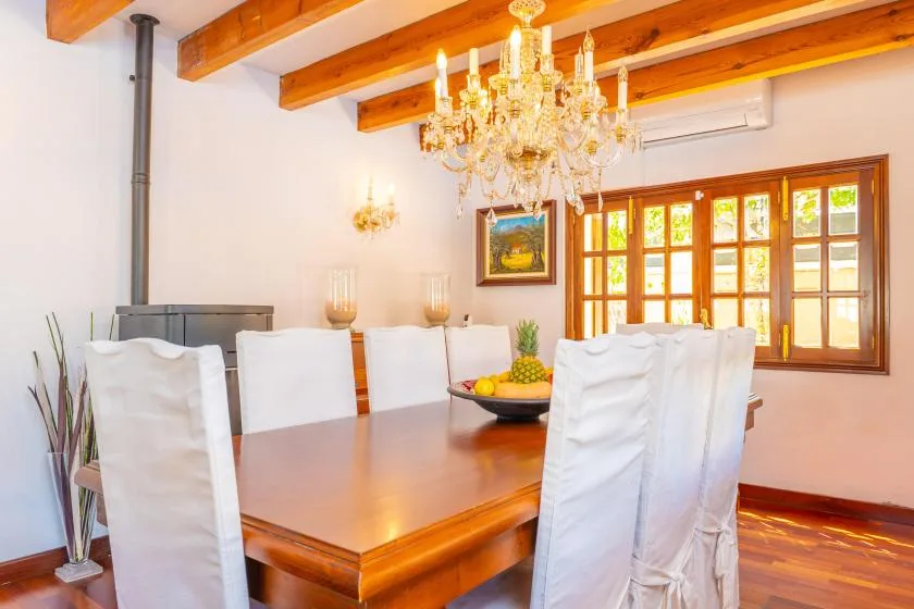 Un comedor con una mesa de madera pulida bajo una lámpara de araña.