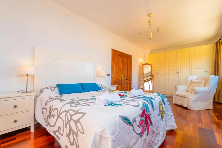 Un dormitorio con una cama grande, armarios empotrados y un sillón tapizado.