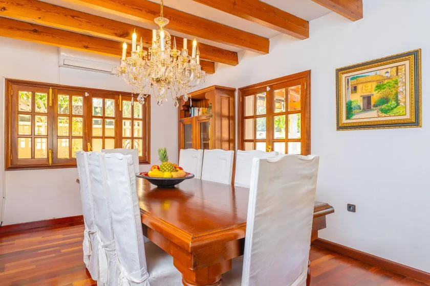 Un comedor con una mesa de madera y sillas bajo una lámpara de araña.