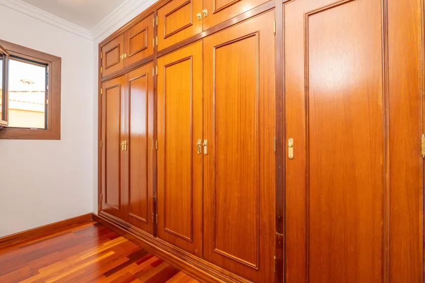 Una habitación con una pared de armarios de madera y una ventana pequeña.