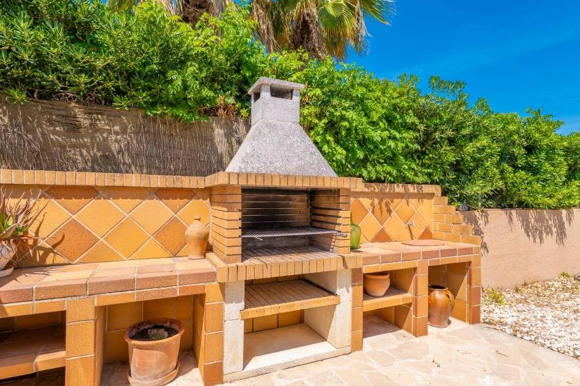 Una zona exterior de barbacoa de ladrillo con chimenea y estantes integrados.