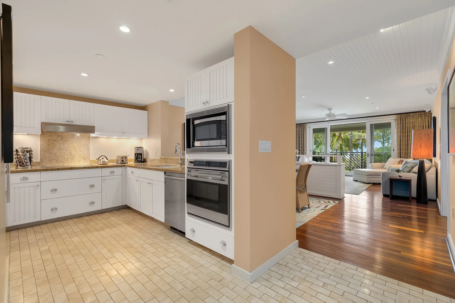 An open-plan kitchen and living area with white cabinetry and a seating area.