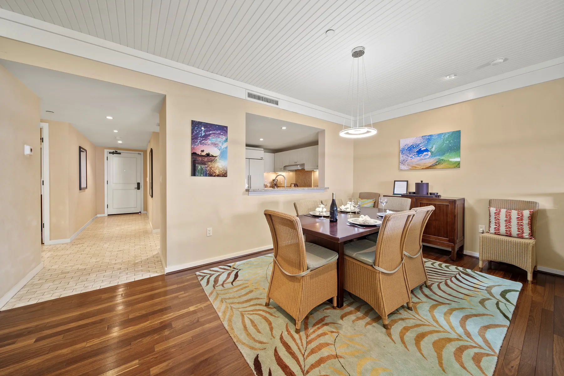 A dining area with a table and wicker seating beside a hallway.
