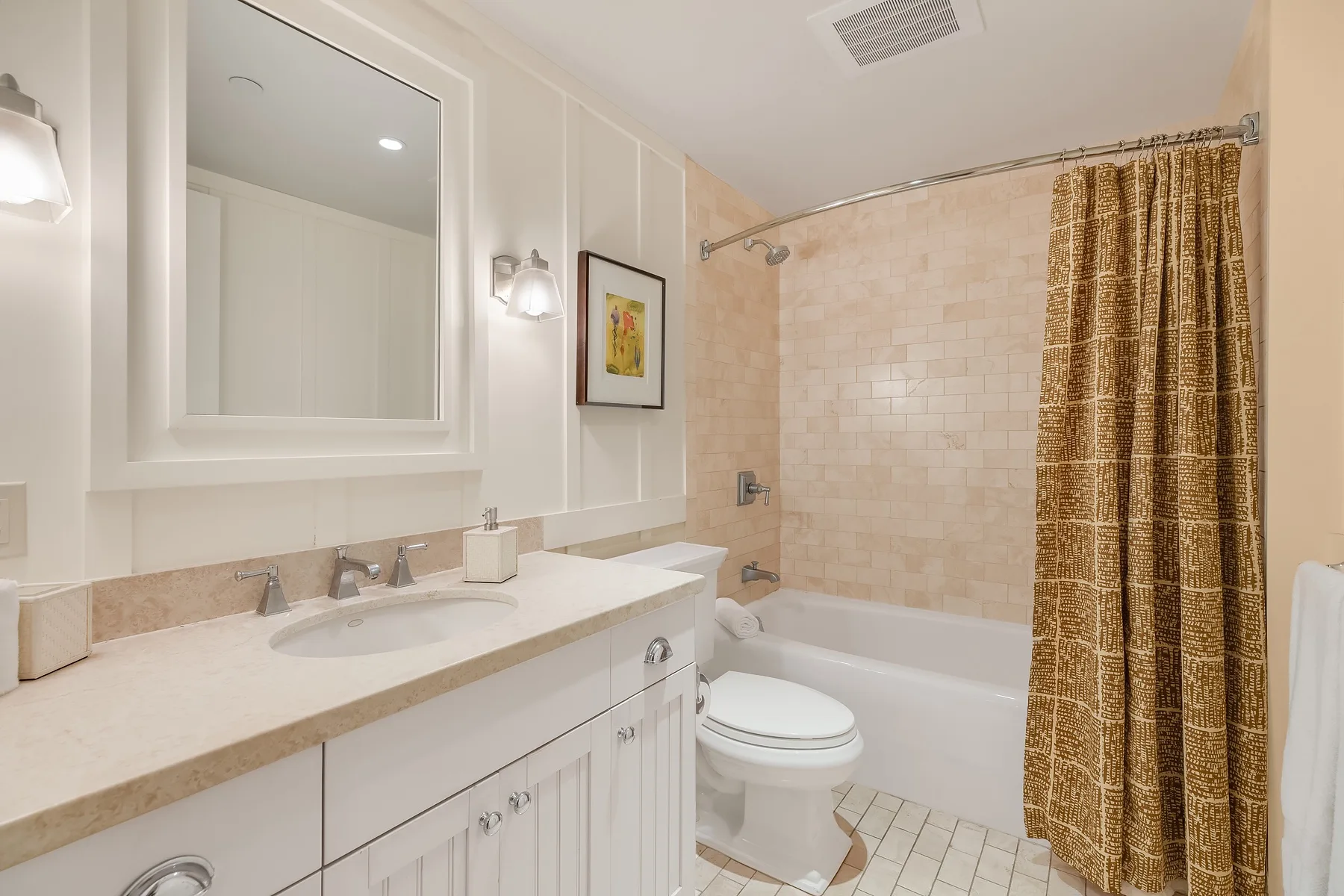 A bright bathroom with a long vanity, mirror, toilet, and bathtub.