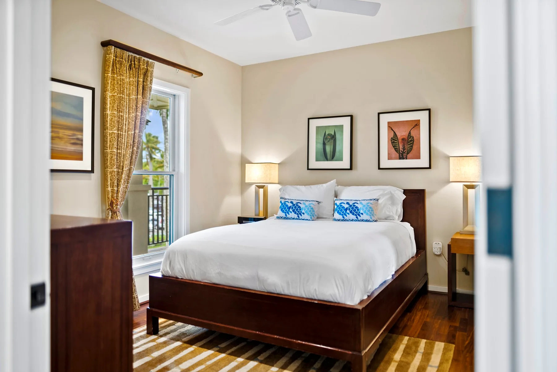 A bedroom with a neatly made bed, bedside lamps, and a glass door.