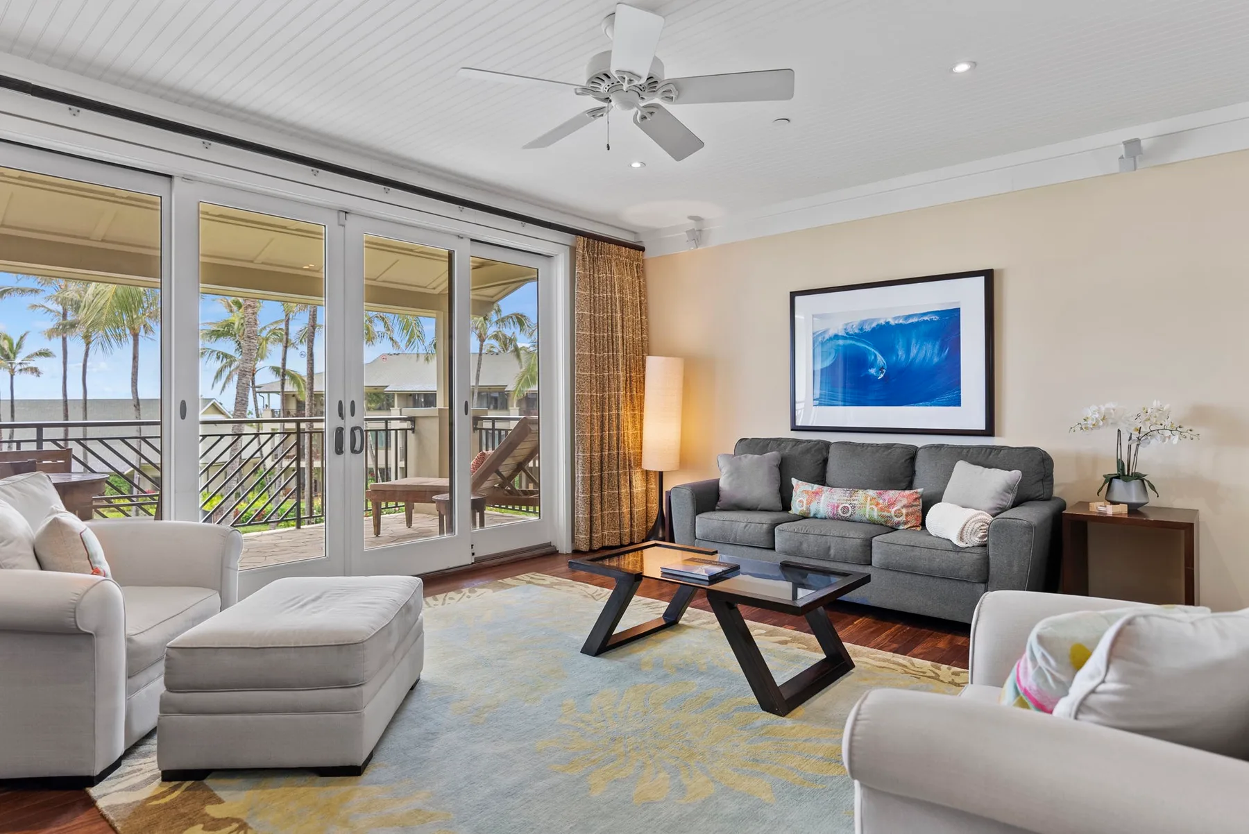 A bright living room with gray seating, a coffee table, and large glass doors.