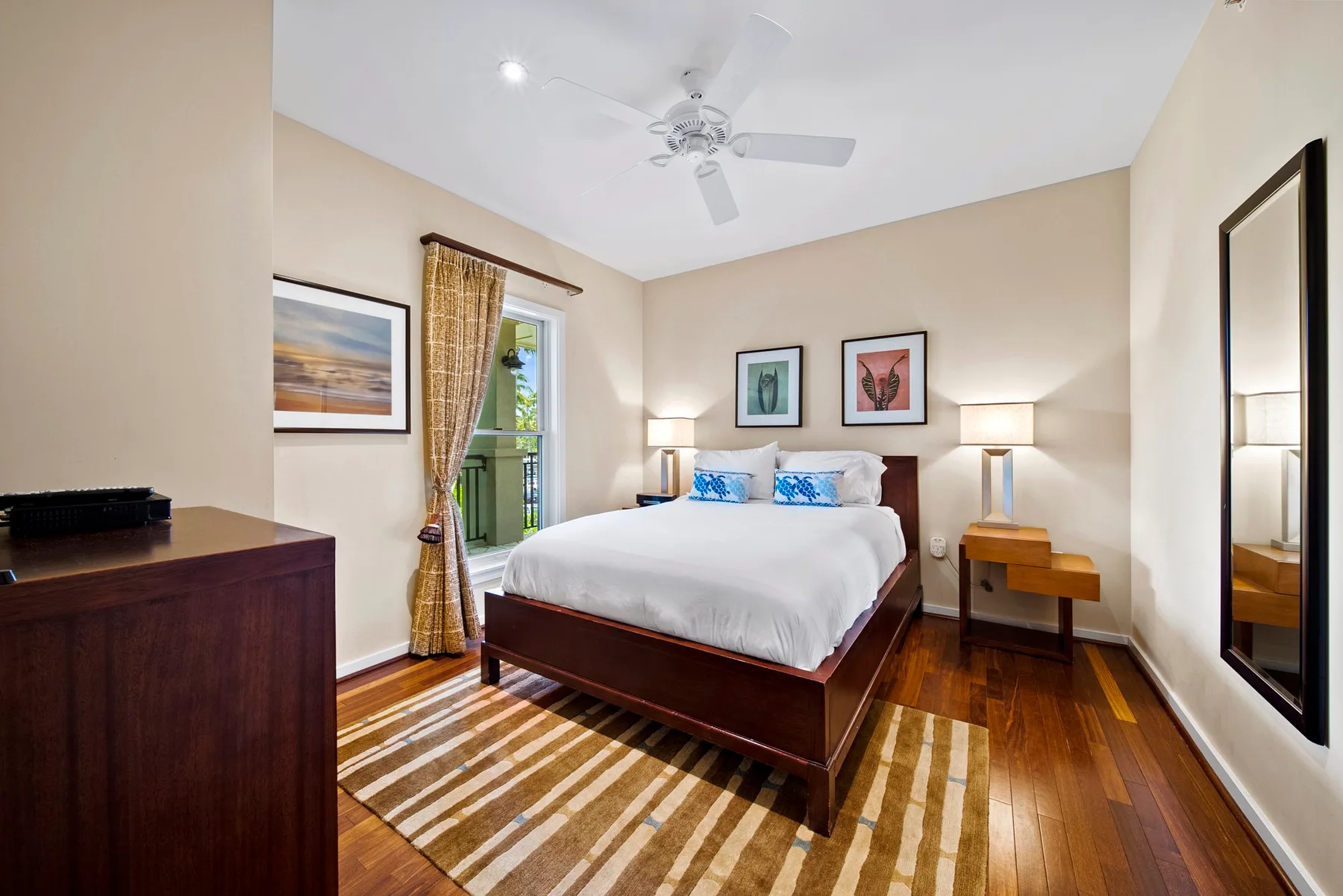 A bedroom with a bed, framed artwork, and a window with curtains.