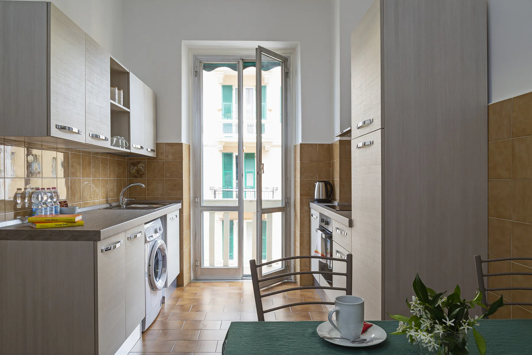 A narrow kitchen with cabinetry, a sink, and a glass door opening onto a balcony.