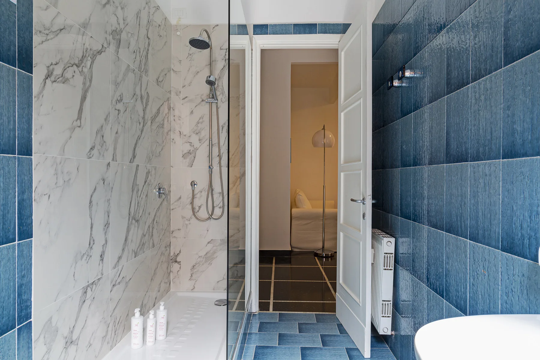 A tiled bathroom with a shower beside an open door.