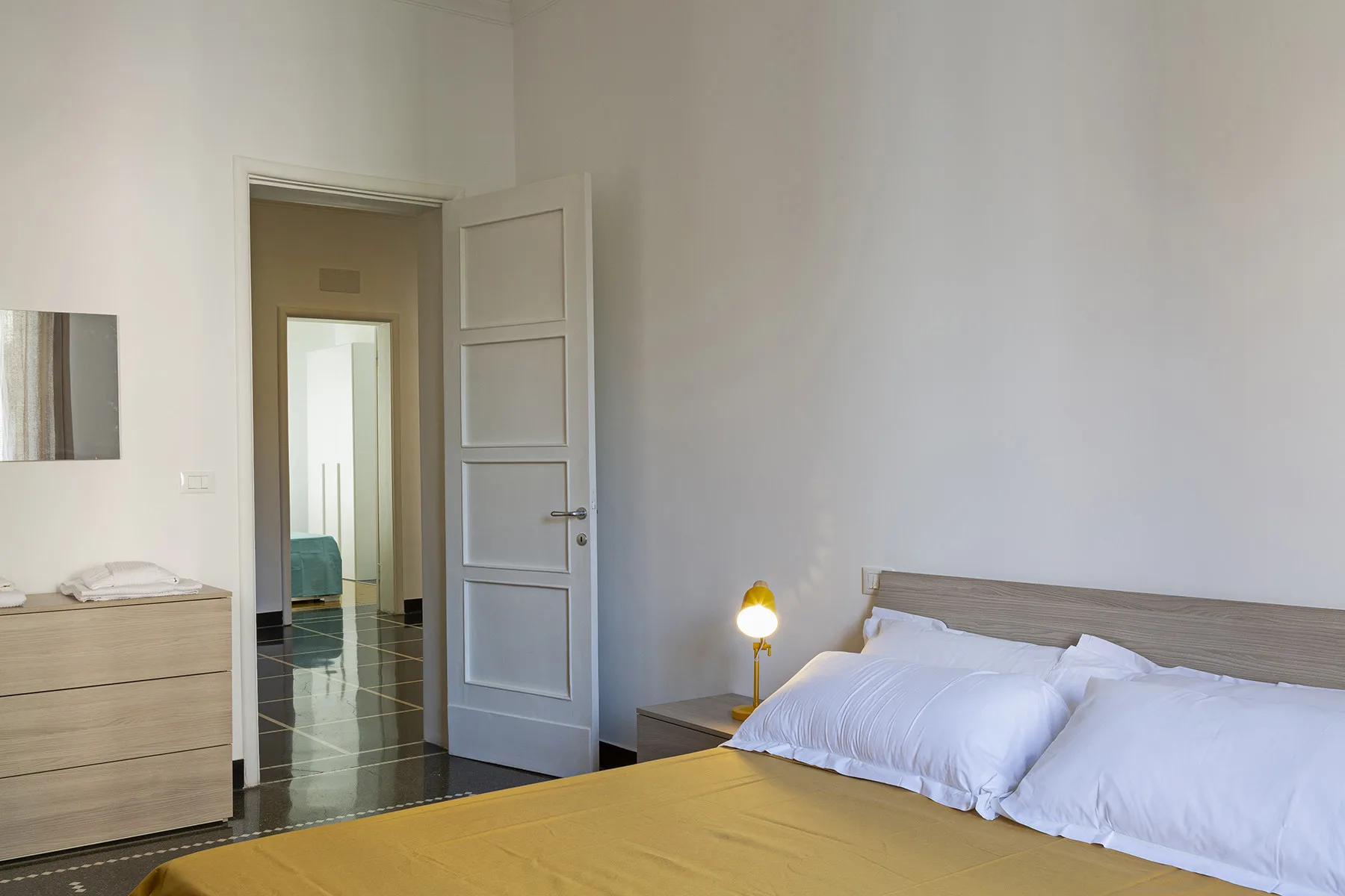 A bedroom with a bed, bedside table, and an open doorway.