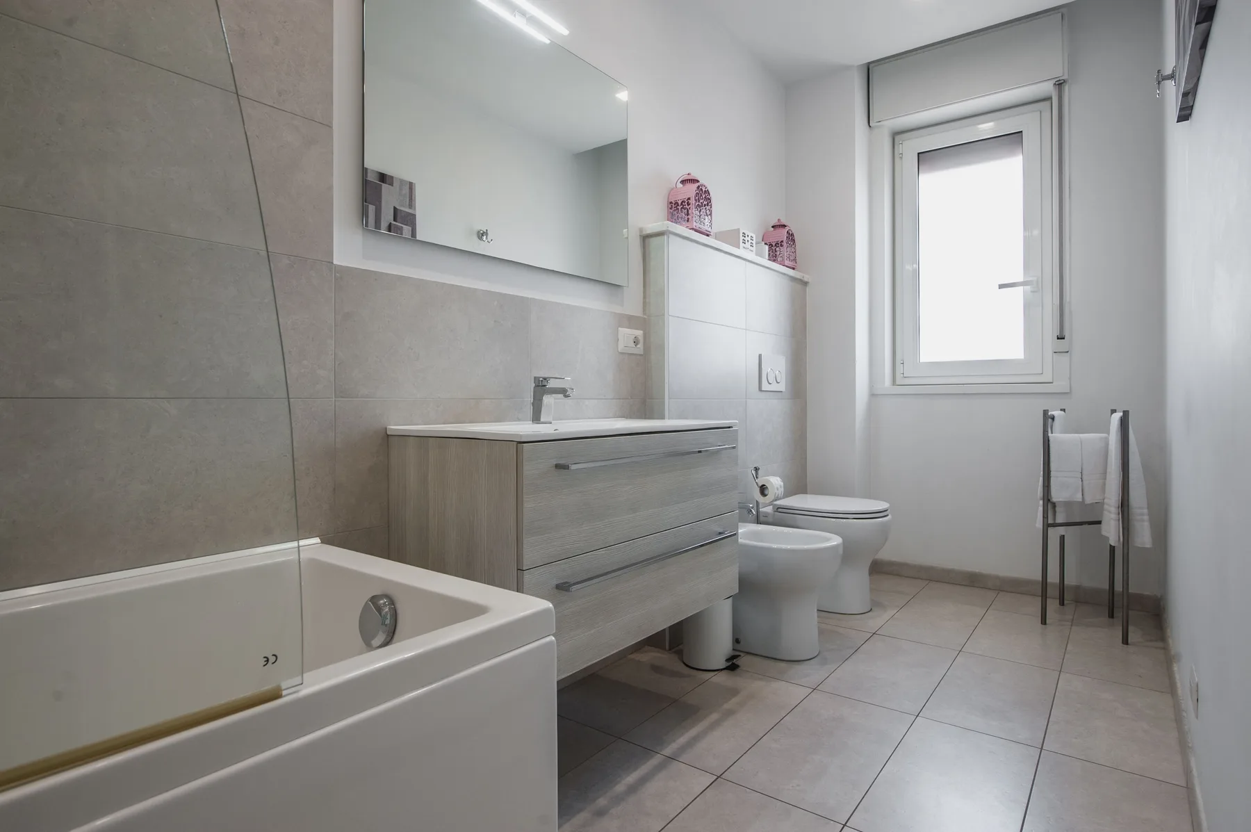 A bathroom with a bathtub, vanity, and window.