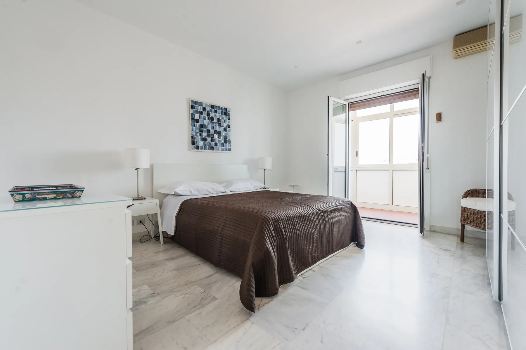 A bright bedroom with a double bed and sliding glass doors.