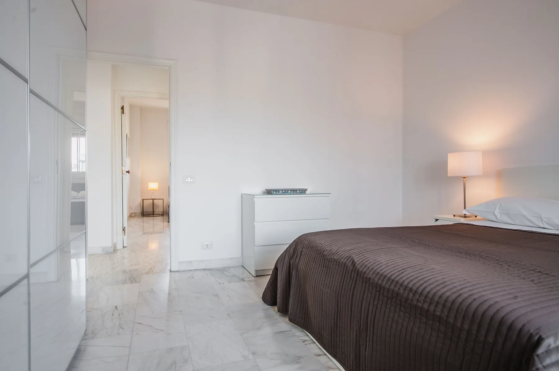 A bright bedroom with a large bed and a white dresser.