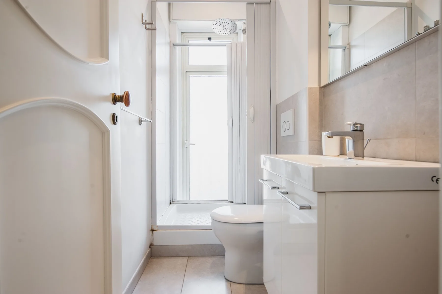 A bright bathroom with a sink, toilet, and shower.