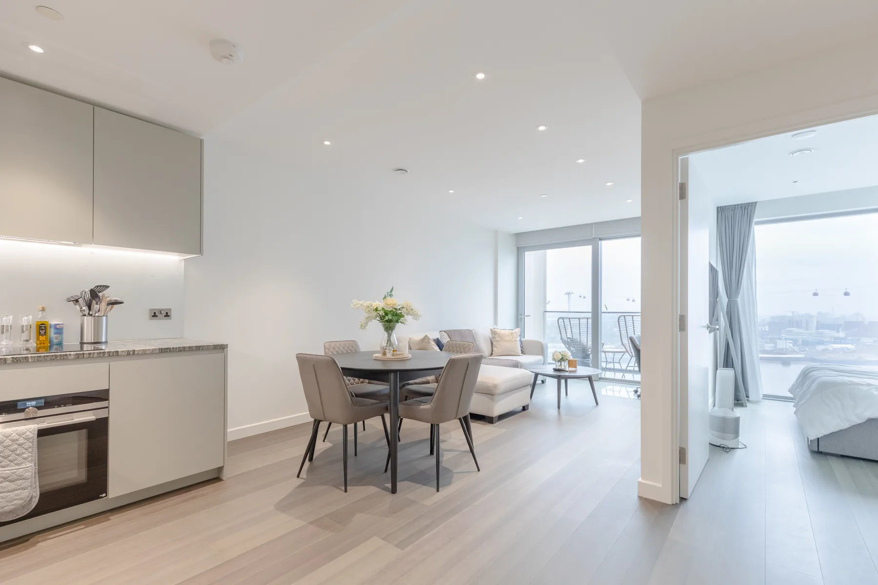 A bright open-plan kitchen and dining area with seating beside a living room.