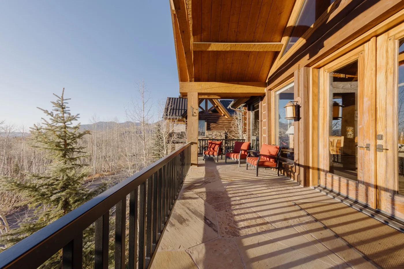 Una terraza exterior de madera con asientos da a un paisaje boscoso.