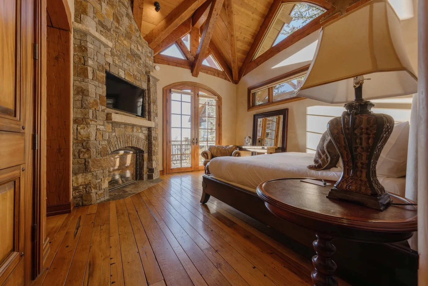 Un dormitorio con cama, chimenea de piedra y techo con vigas de madera.
