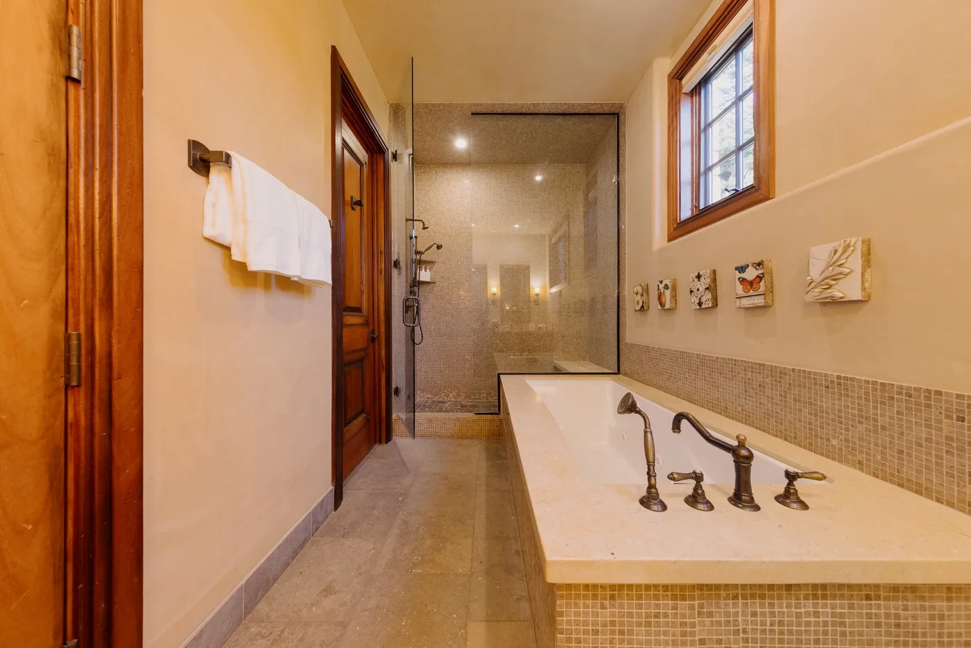 Un baño con bañera, grifos en la pared y una zona de ducha acristalada.