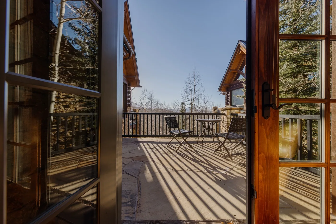 Una terraza de madera soleada con asientos al aire libre y vistas a los árboles.