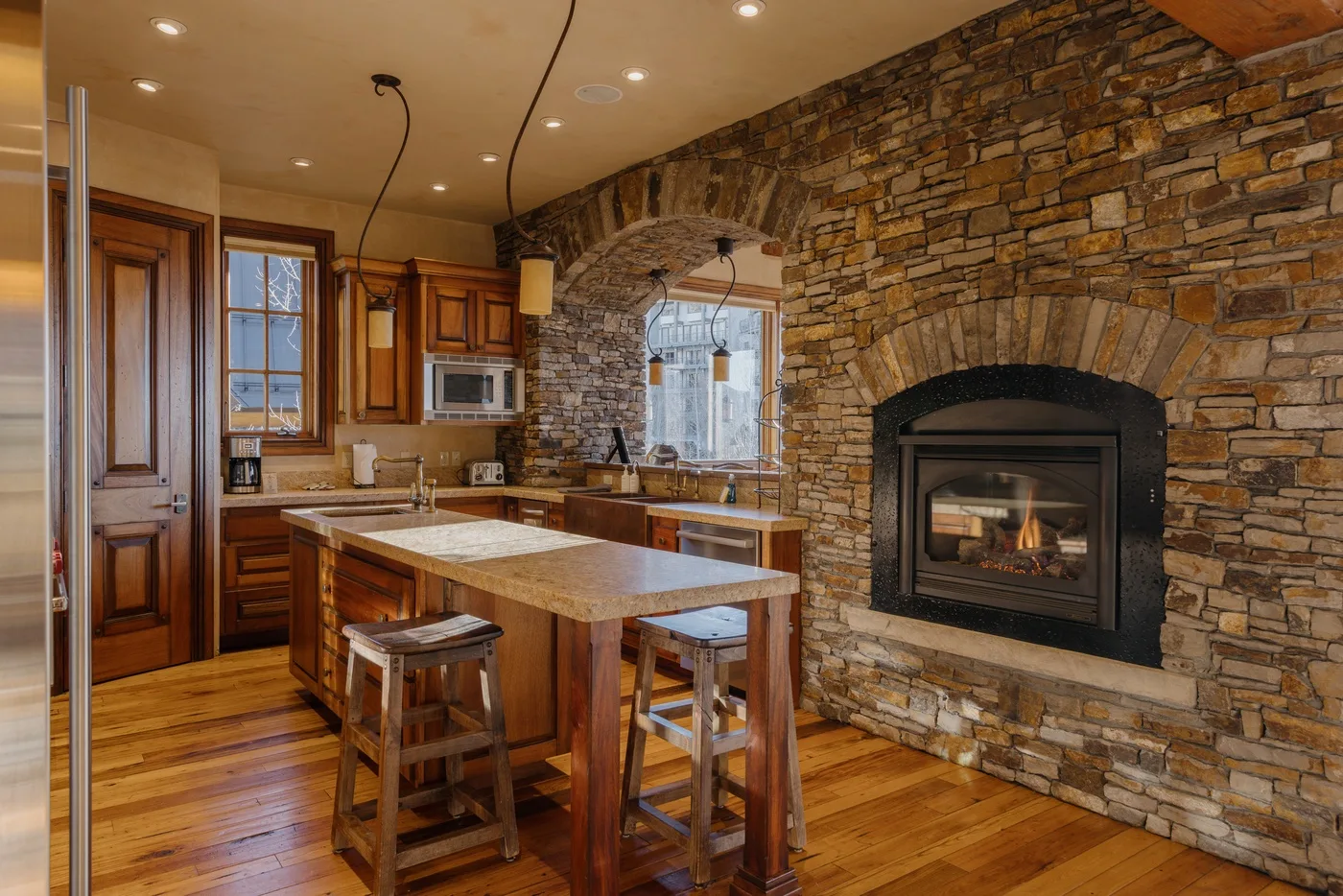 Una cocina rústica con una isla central y una chimenea de piedra.