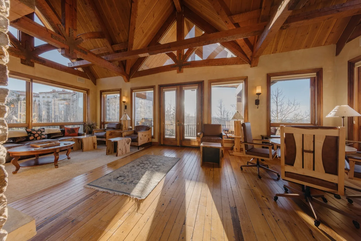 Una amplia sala con vigas de madera, grandes ventanas y suelo de madera pulida.