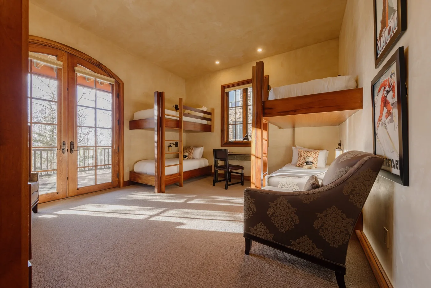 Un dormitorio con literas de madera, un escritorio pequeño y puertas de vidrio que dan a un balcón.