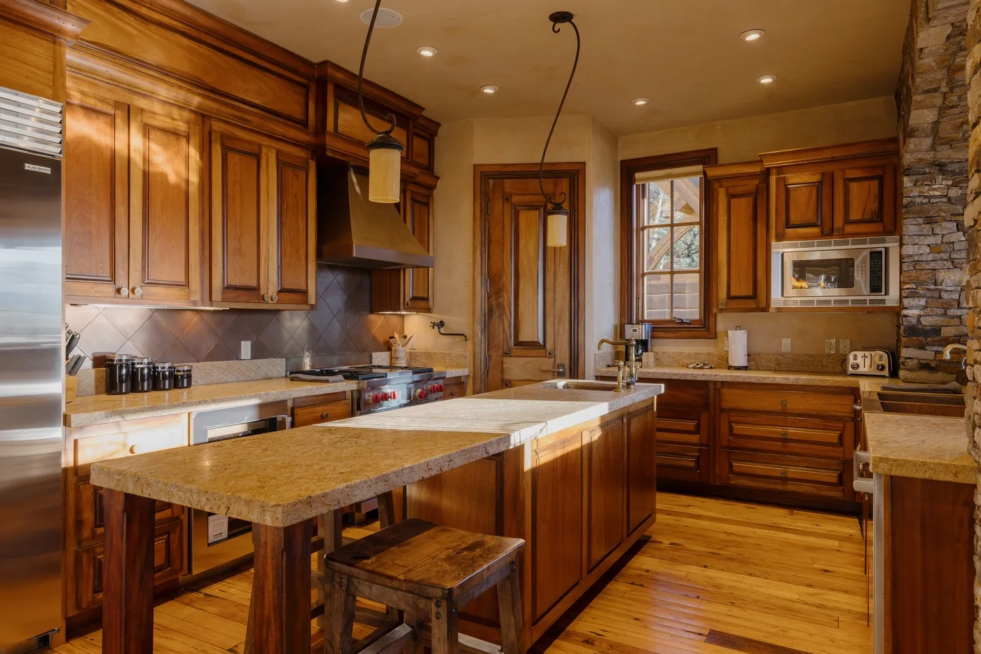 Una cocina amplia con gabinetes de madera, una isla central y encimeras de piedra.